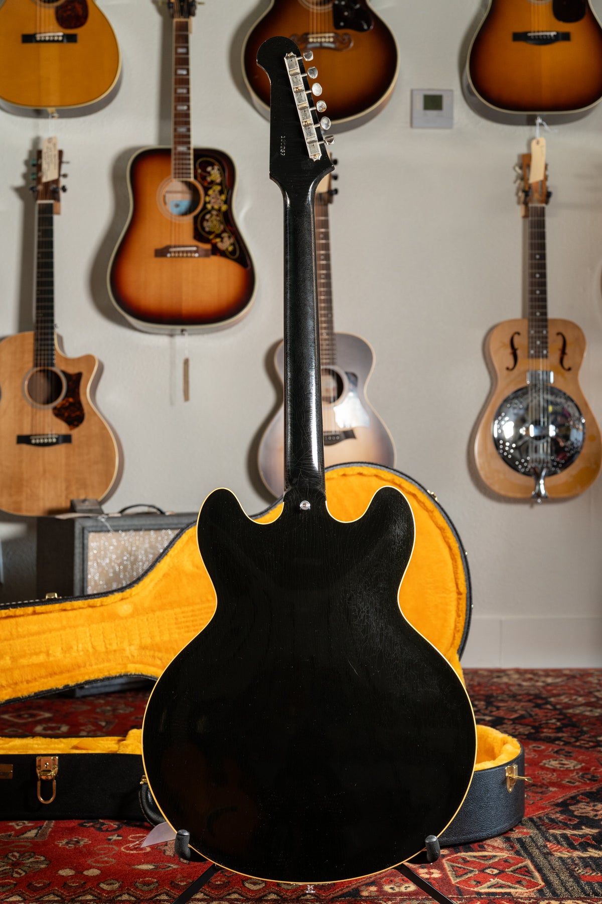 The back of a black semi-hollow electric guitar with a bound body, showing light finish checking and a matching headstock.