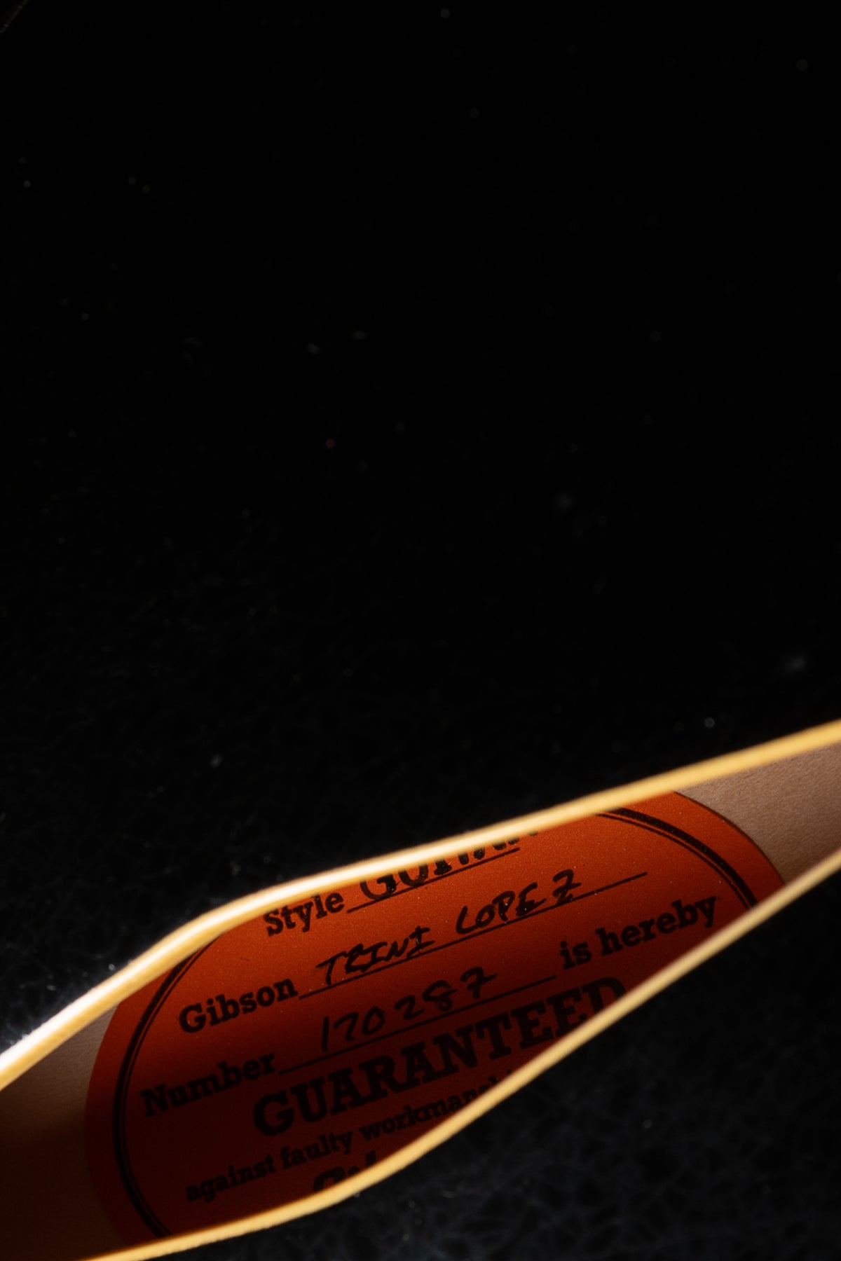A close-up of the orange oval label inside the guitar's f-hole, showing "Gibson Trini Lopez" and a serial number.