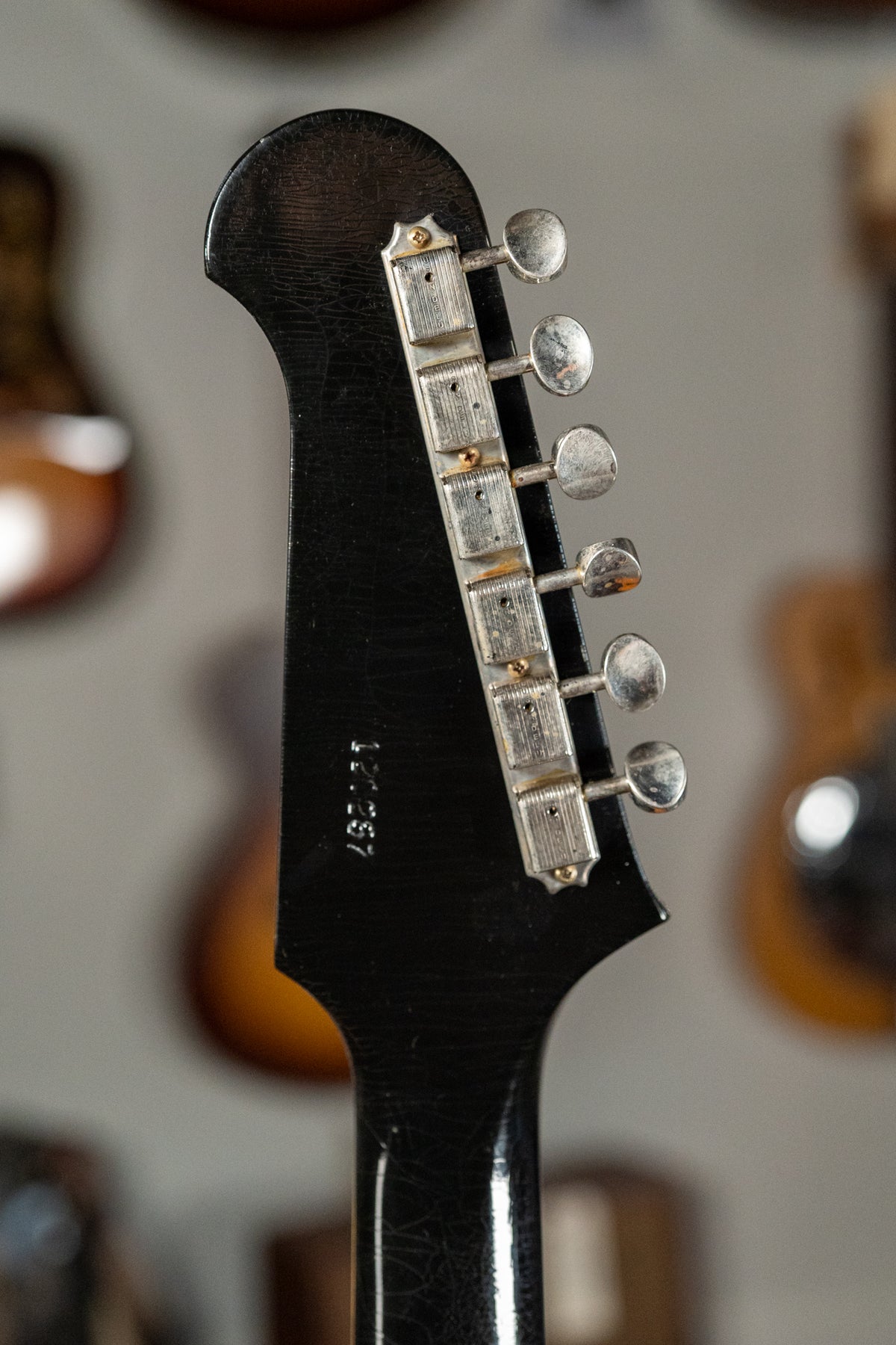 Close-up of the black headstock and top of the neck, showing extensive finish checking and six aged nickel tuners.