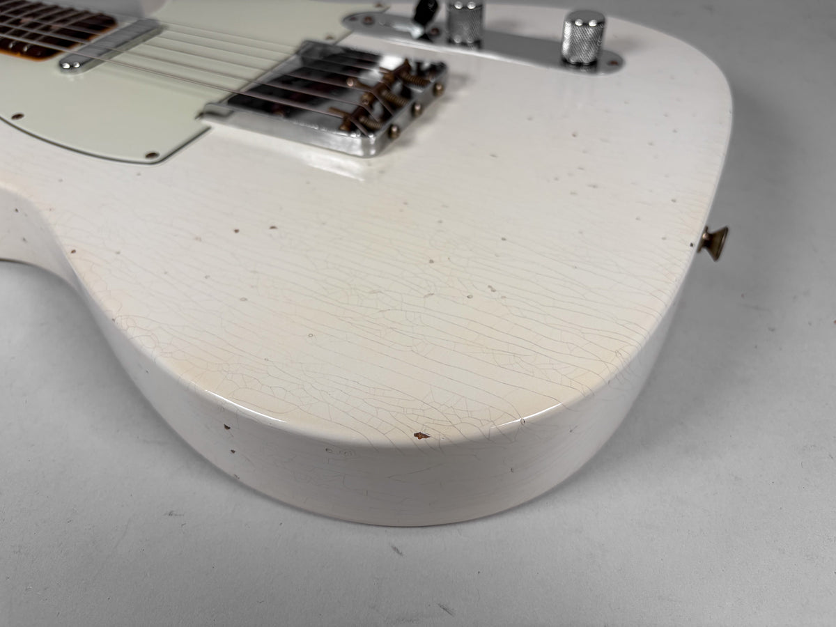 Close-up of the lower bout of an Olympic White Telecaster, showing extensive finish checking, dings, and a worn chrome bridge.