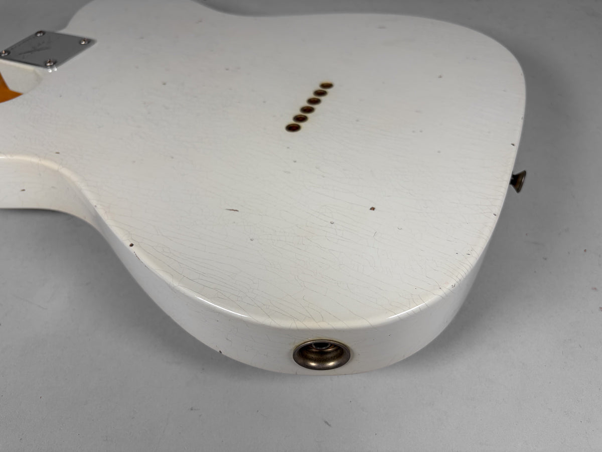 The back of an Olympic White guitar body, showing heavy finish checking, six string-through-body ferrules, and a strap button.