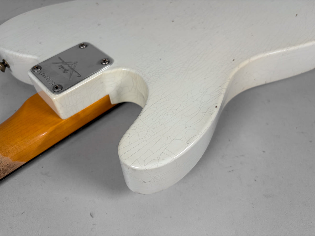 The guitar's Olympic White body shows extensive finish checking and small dark dings, with a chrome neck plate and amber-toned neck.