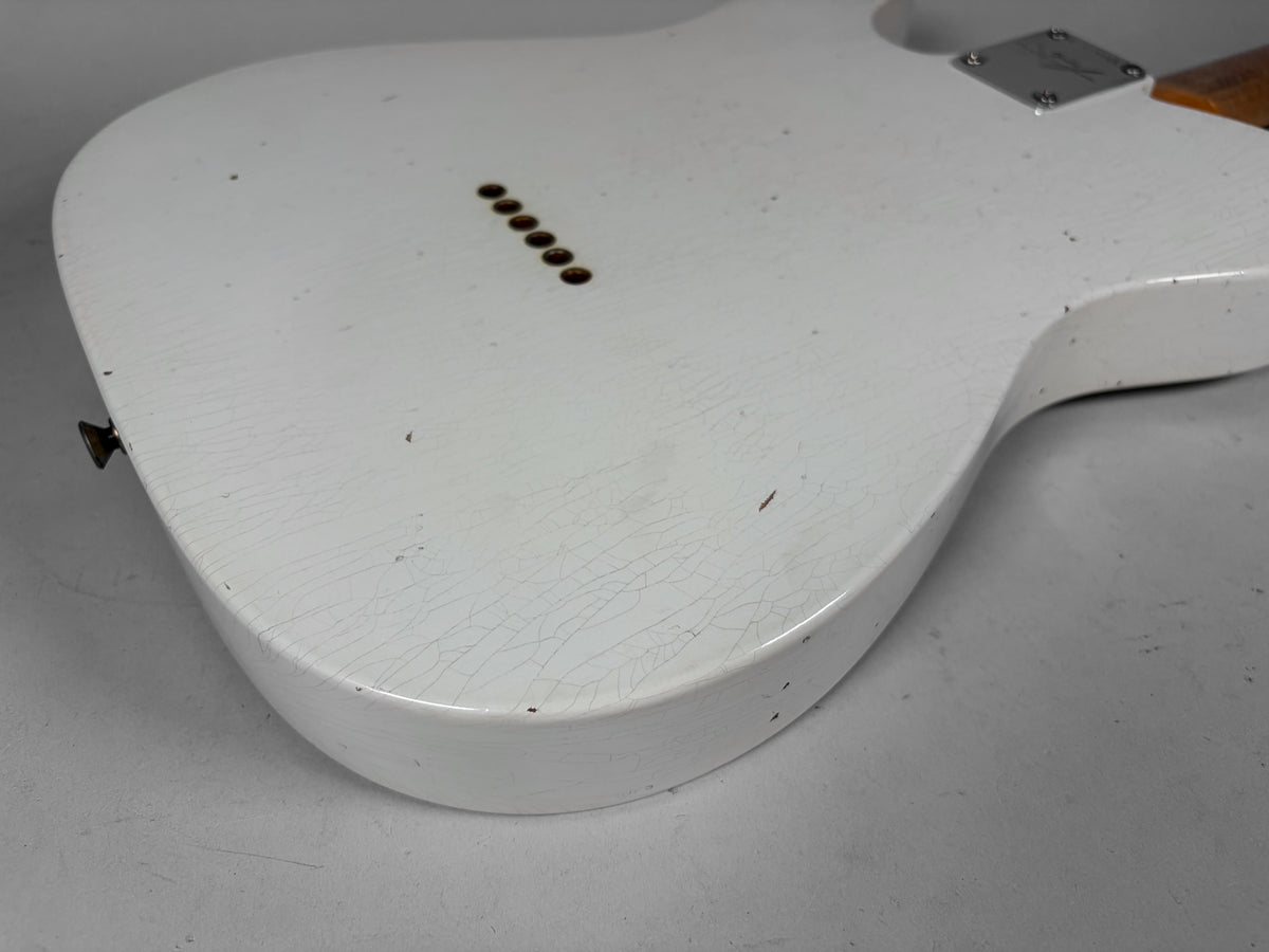 The back of a white guitar body, showing extensive finish checking, small chips, and six string-through-body ferrules.