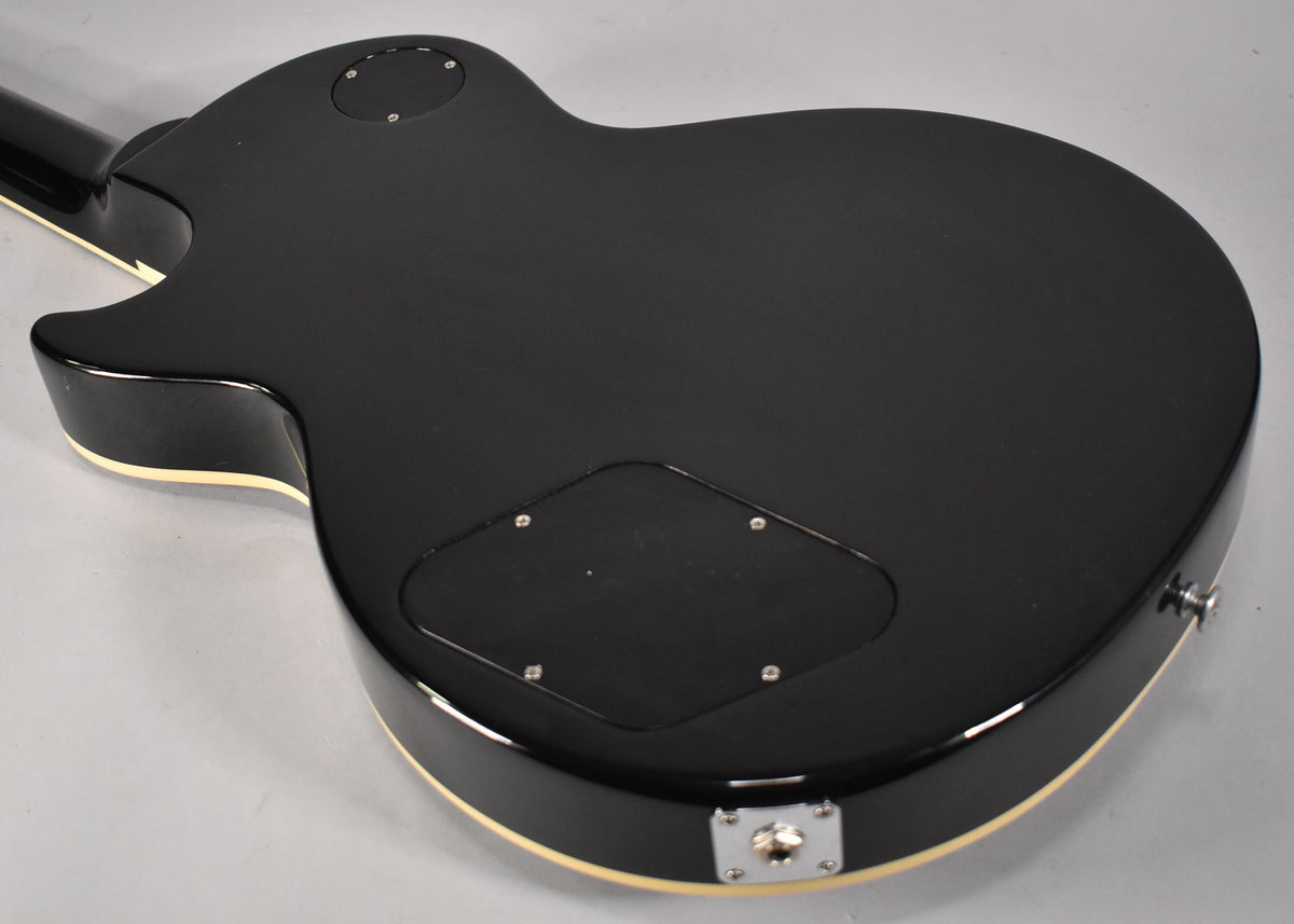 The guitar's black matte back shows two control cavity covers, a chrome output jack, and a strap button.