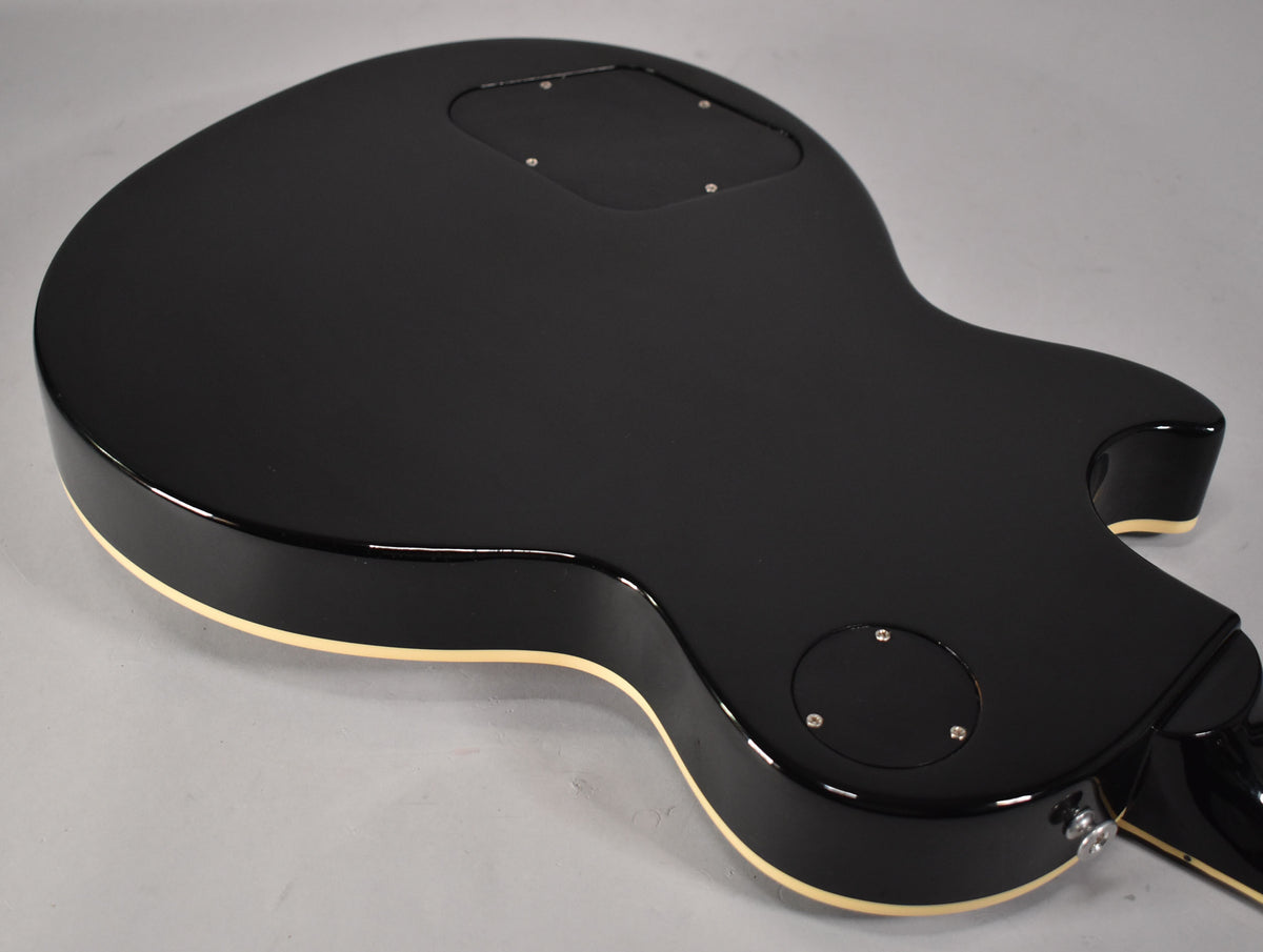 The back of the guitar, finished in glossy black with cream binding, showing the control cavity and switch plate covers.