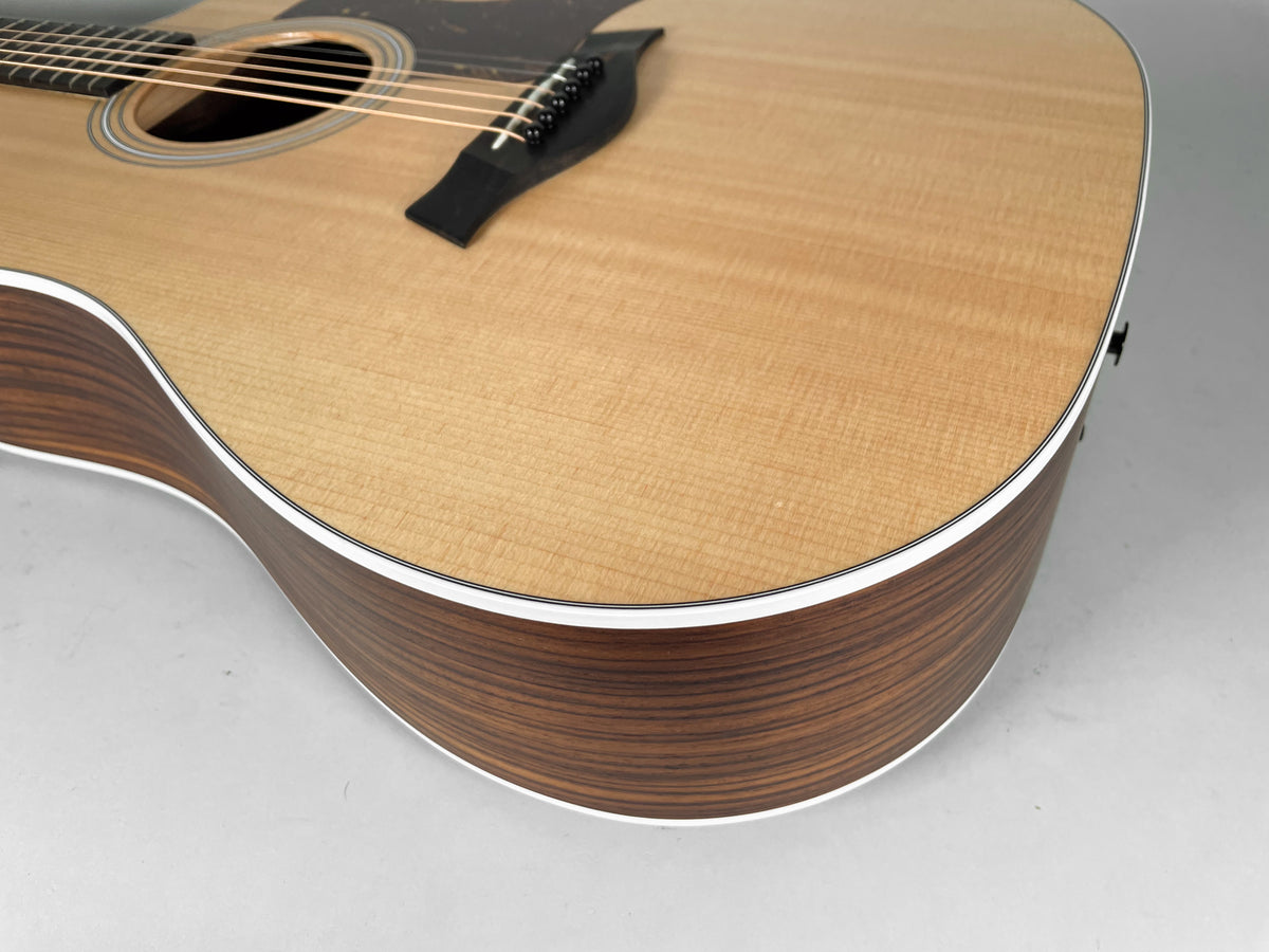 Close-up of the natural finish acoustic guitar's lower bout, showing the light wood top, dark wood sides, and white binding.