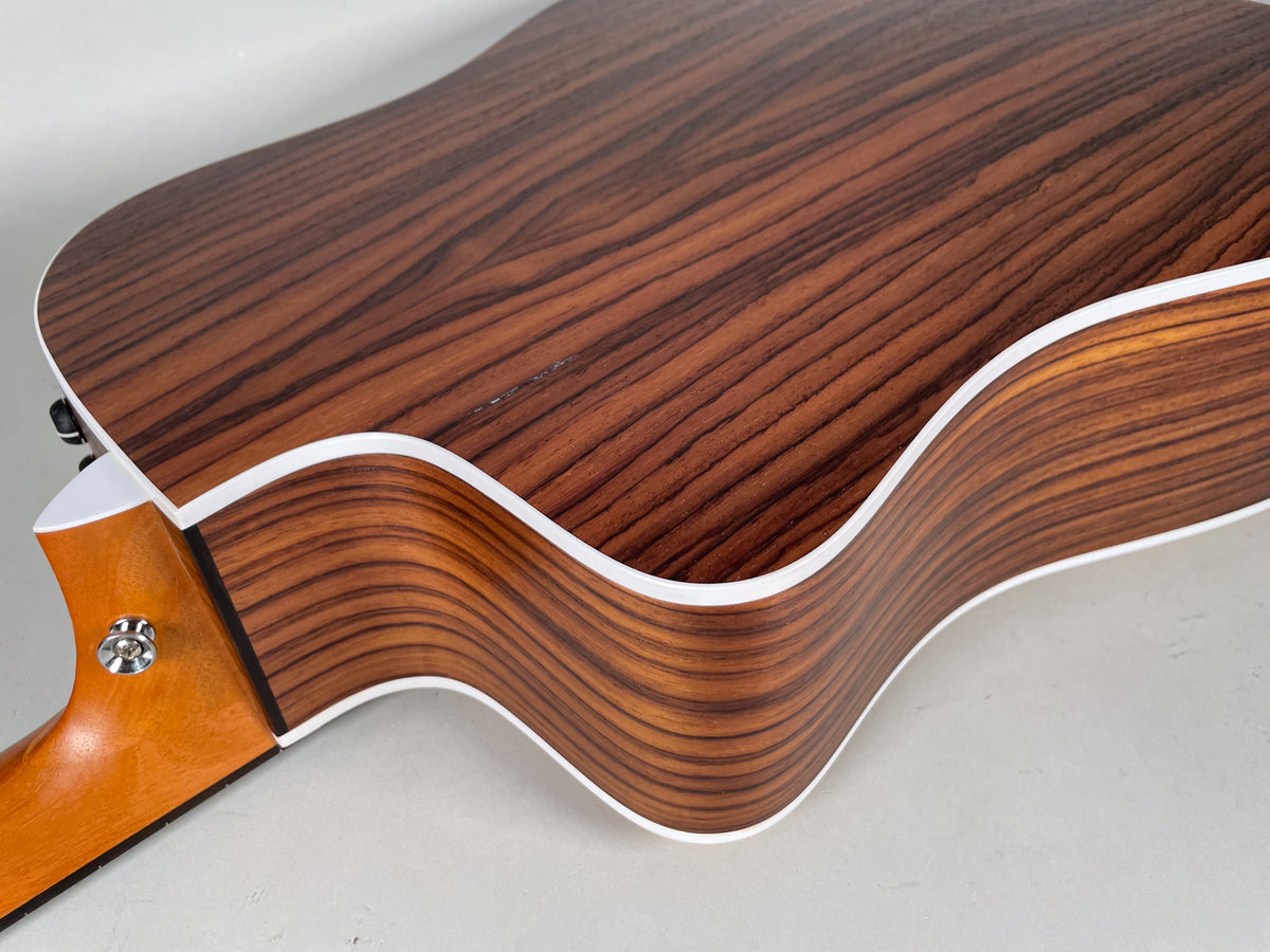 The guitar's dark brown wood grain back and side with white binding is angled from the neck joint to the lower bout.