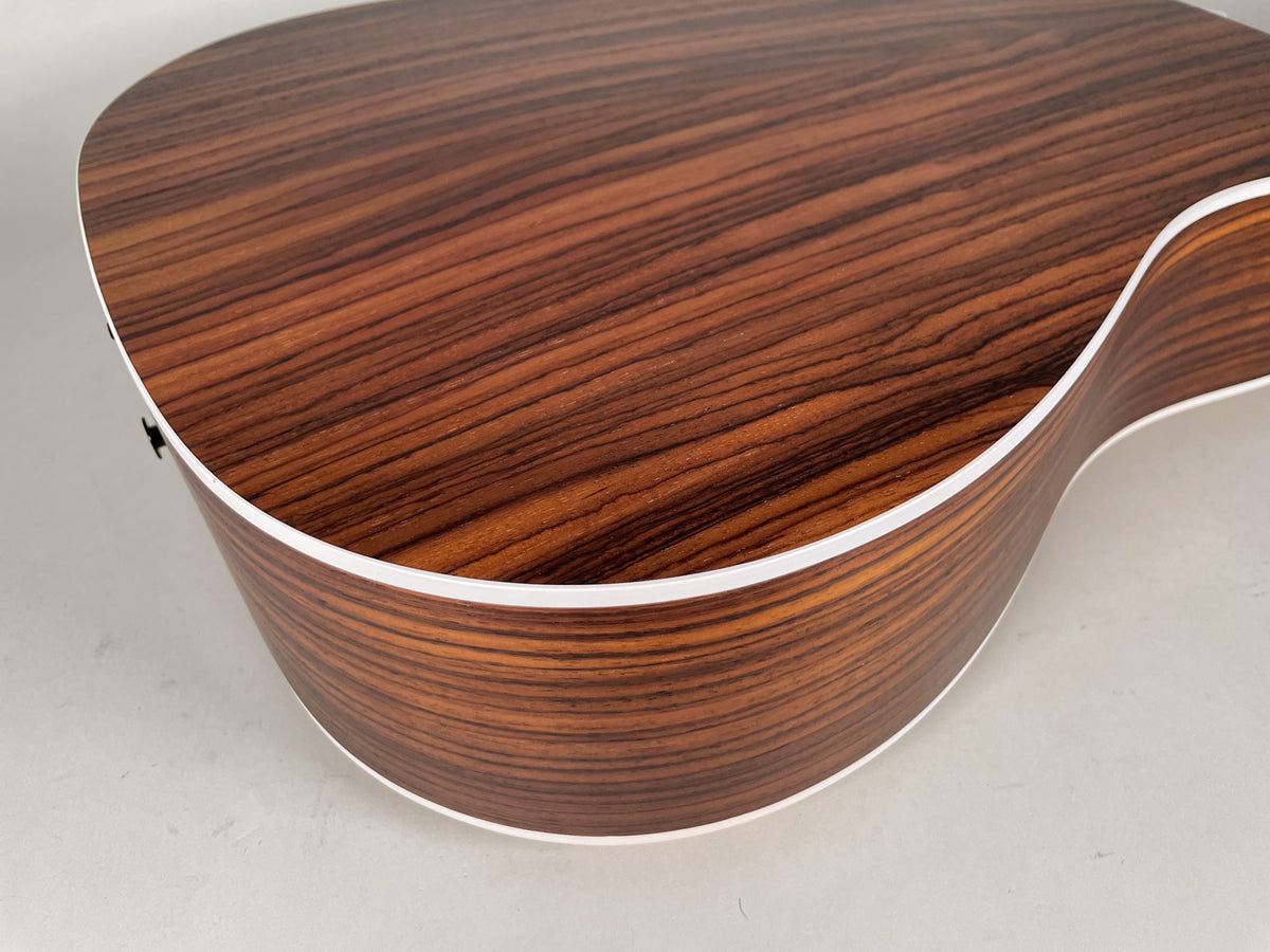 Close-up of the guitar's lower bout, showing the dark brown wood grain with white binding along the top and bottom edges.