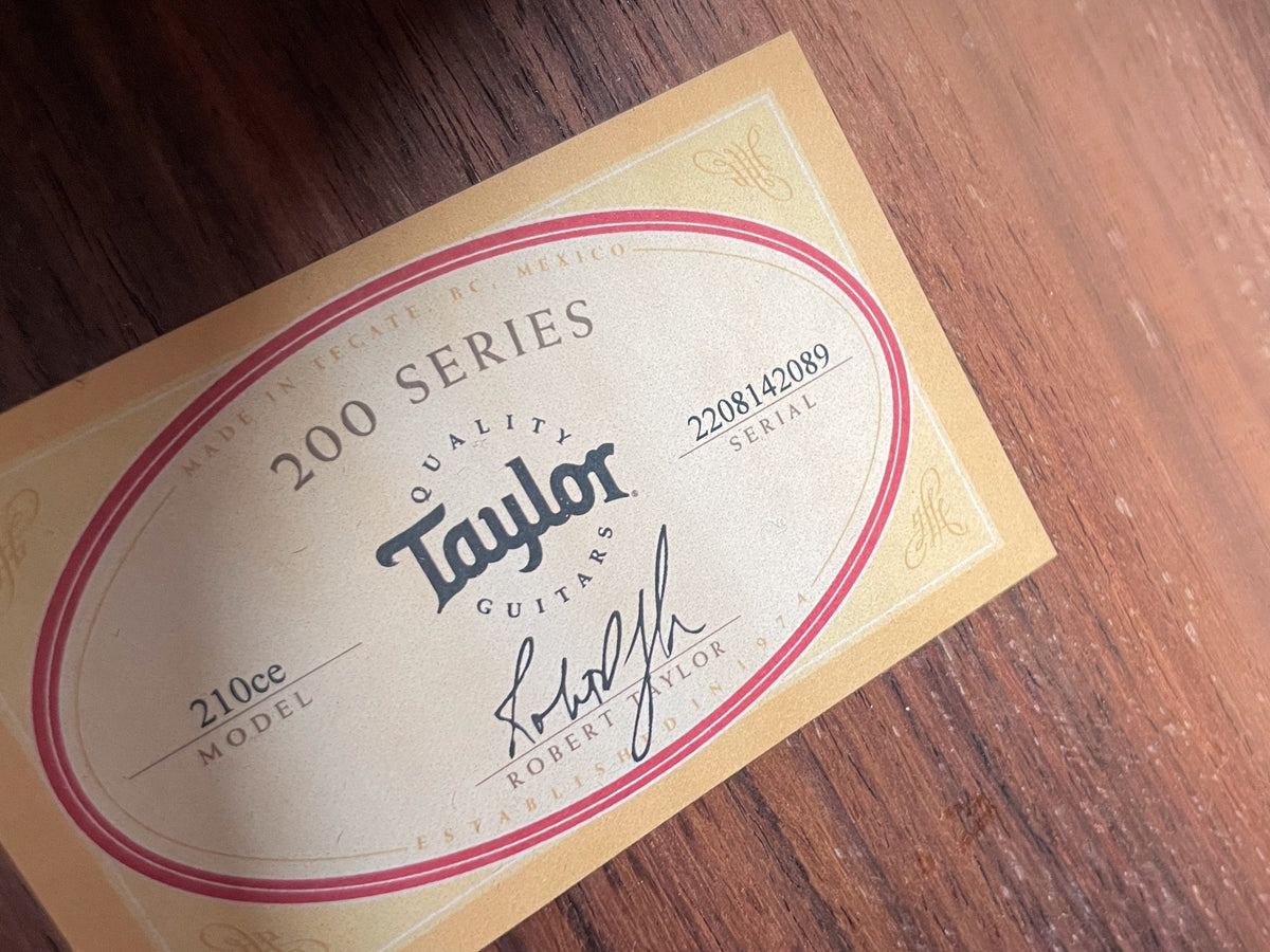Close-up of the guitar's internal label, showing "200 SERIES" and "210ce MODEL" on a light tan background with red trim.