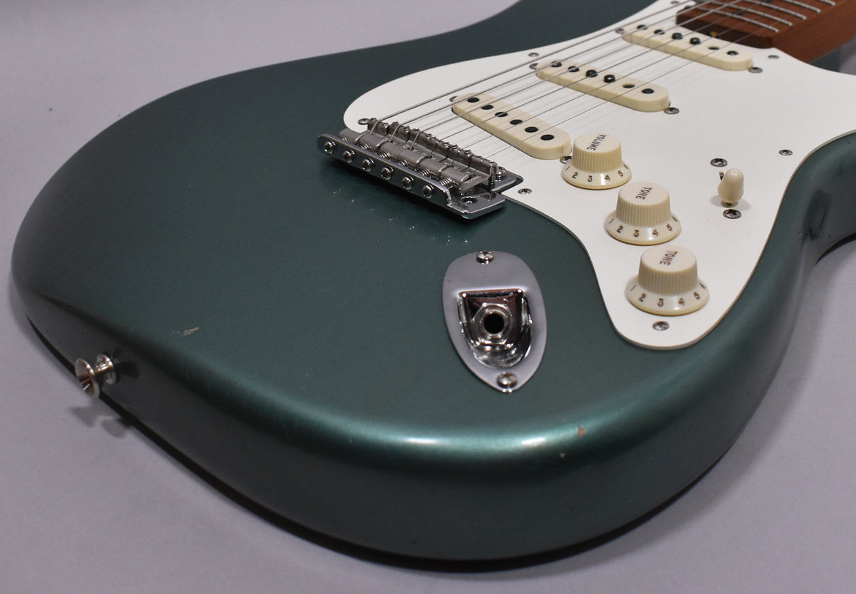 Close-up of the Sherwood Metallic body, showing the output jack, bridge, white pickguard, three cream control knobs, and light relic wear.