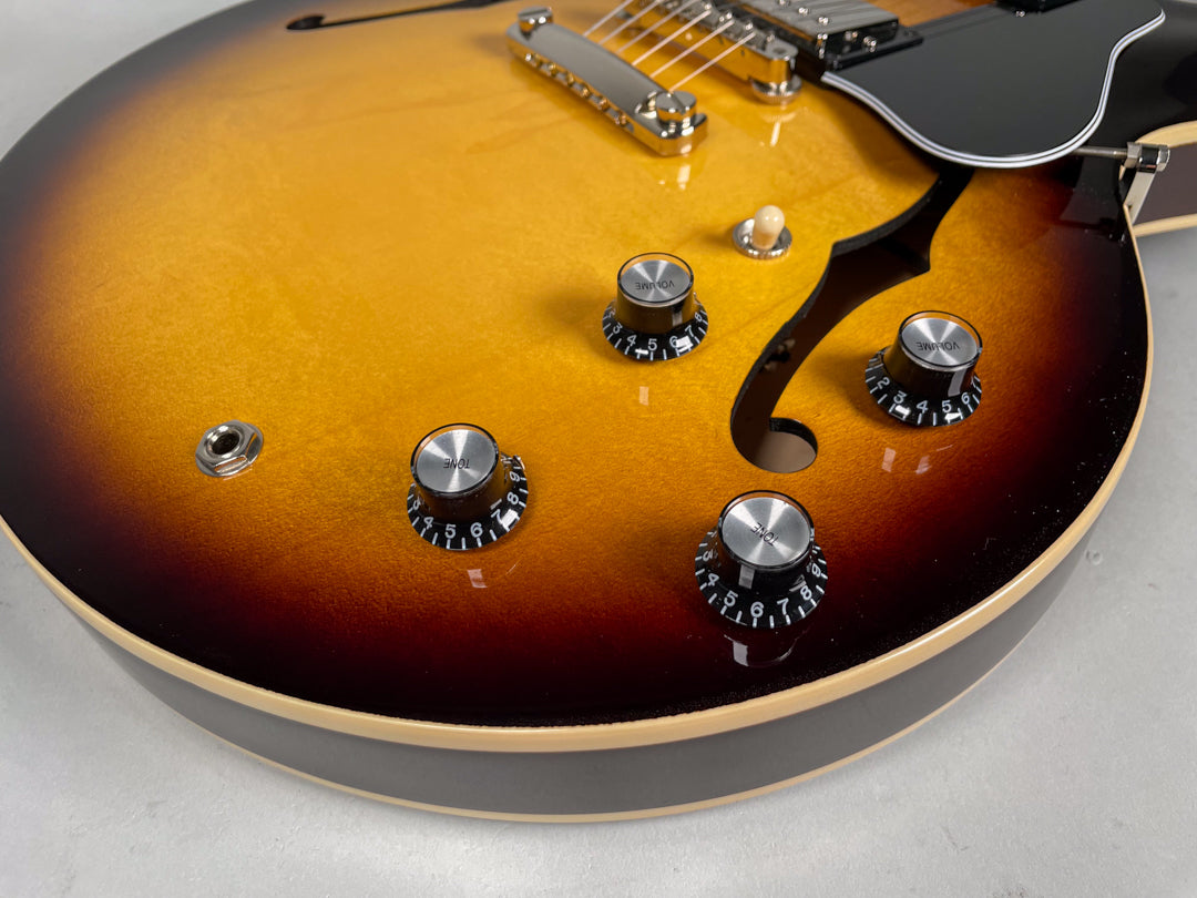 Close-up of the sunburst body, showing the output jack, four black control knobs with silver tops, and the lower f-hole.
