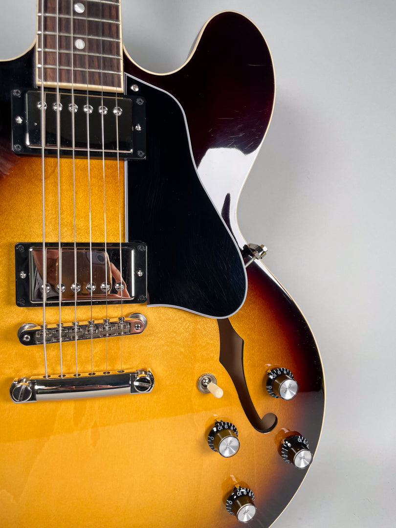 Close-up of the sunburst body, showing the black pickguard, two humbuckers, bridge, F-hole, and four control knobs.