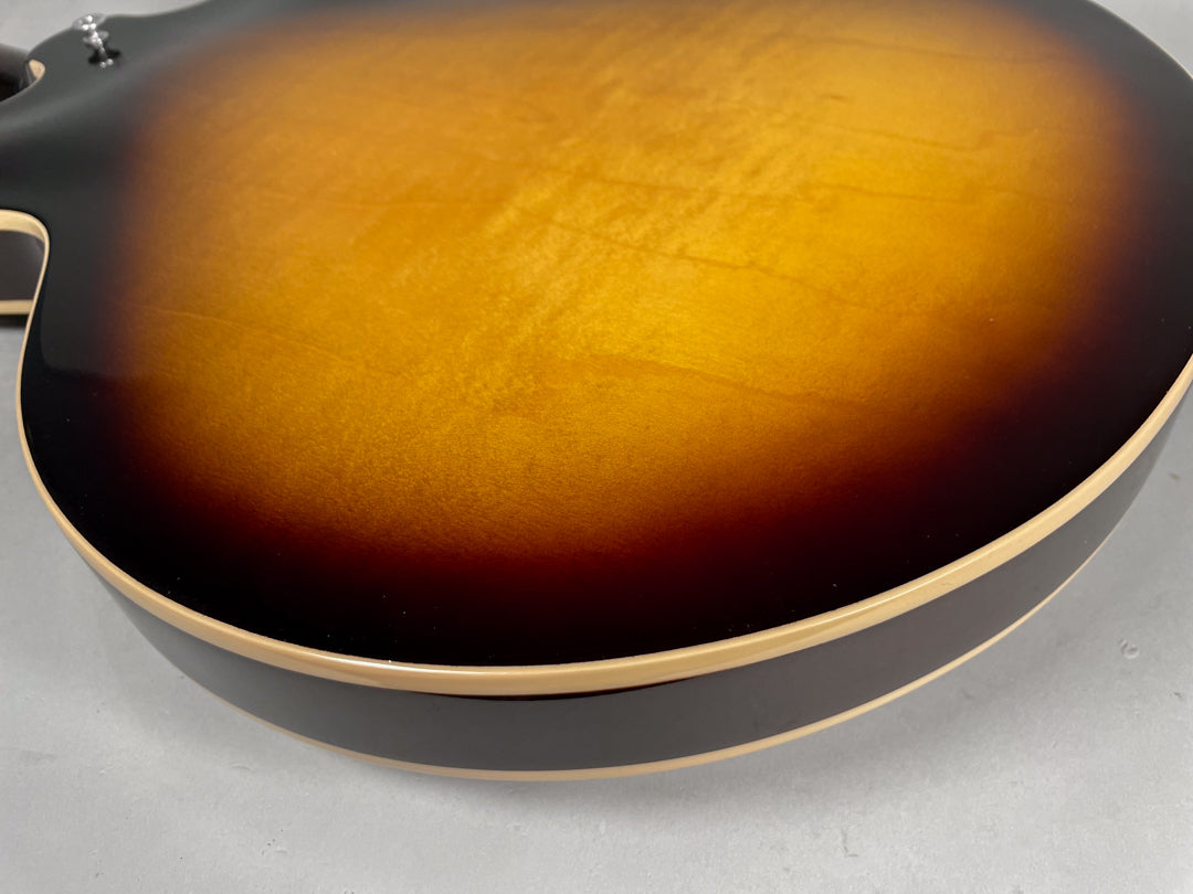 Close-up of the guitar's sunburst body, showing the dark brown edges fading to a bright amber center, with light binding and minor surface scratches.