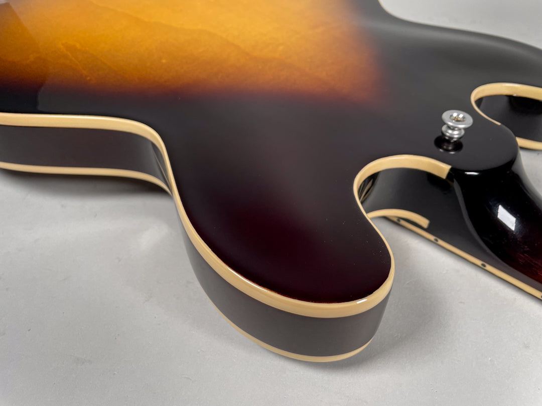 Close-up of the guitar's lower bout and cutaways, showing the sunburst finish, cream binding, and a chrome strap button.