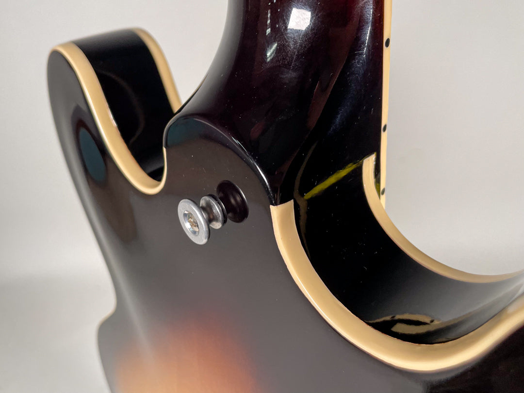 Close-up of the sunburst body and neck joint, showing the upper strap button and cream binding on the cutaway.
