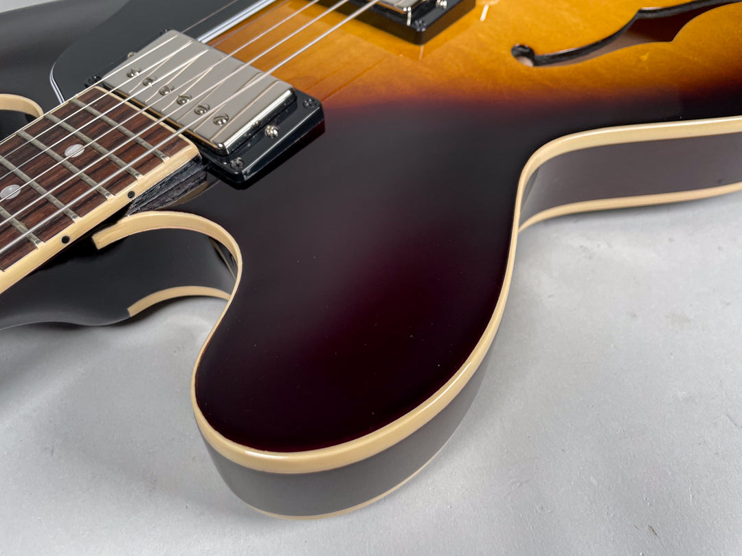Close-up of the guitar's lower bout, showing the sunburst finish, cream binding, and part of the neck pickup and fretboard.