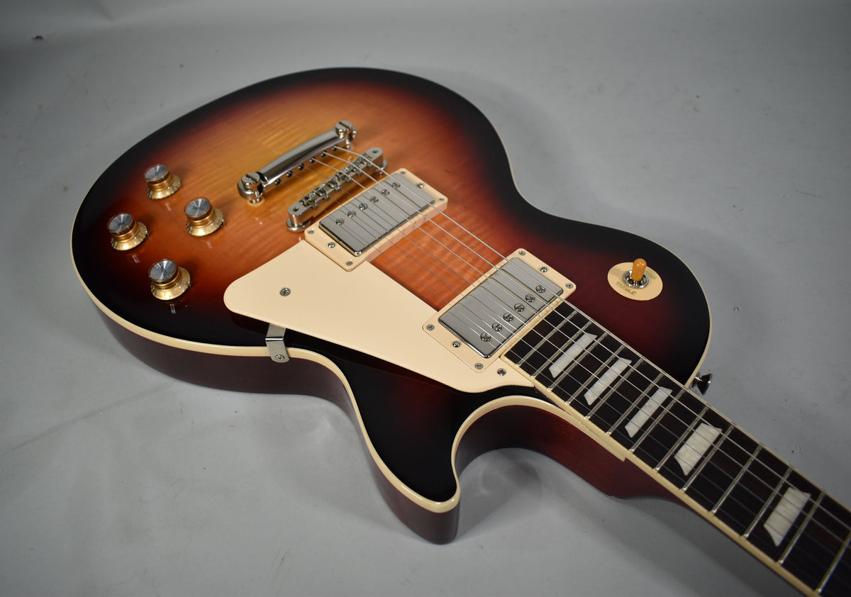 The sunburst electric guitar body, pickguard, and lower neck are visible from above, showing chrome hardware and trapezoid inlays.
