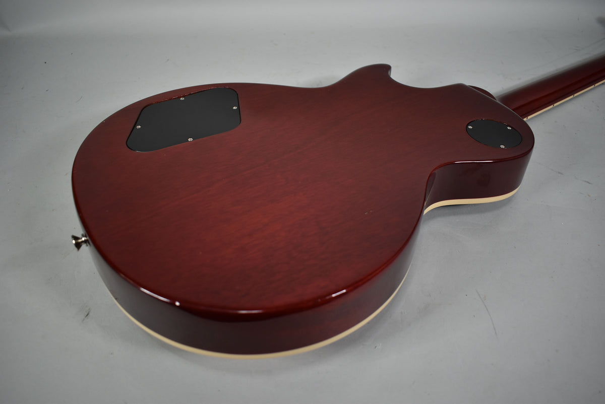 The back of a cherry sunburst guitar, showing the control cavity and switch plate covers, with light binding and a strap button.