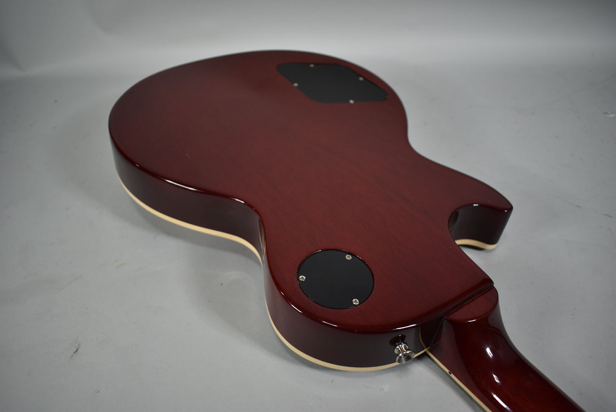 The guitar's cherry red back, with cream binding, is angled from the lower bout to the cutaway, showing two black control plates.
