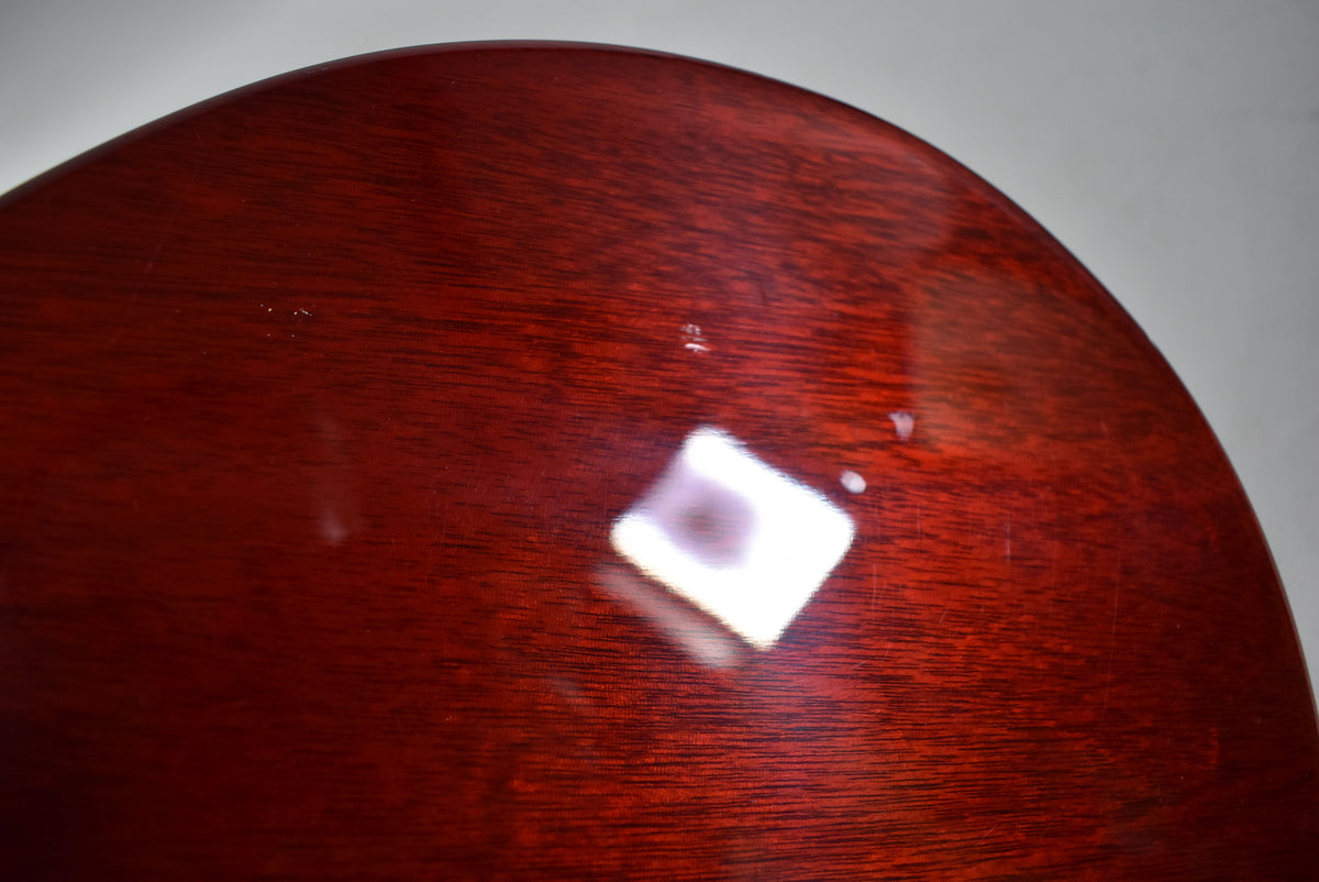 Close-up of the guitar's dark red mahogany back, showing light surface scratches and a few small dings in the glossy finish.