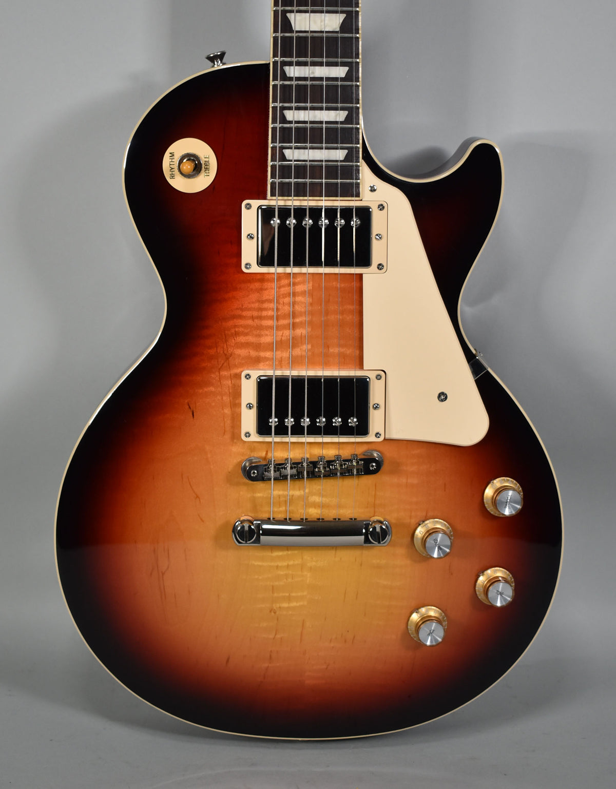 Full front view of a sunburst electric guitar with a flamed maple top, cream binding, and four gold-capped control knobs.