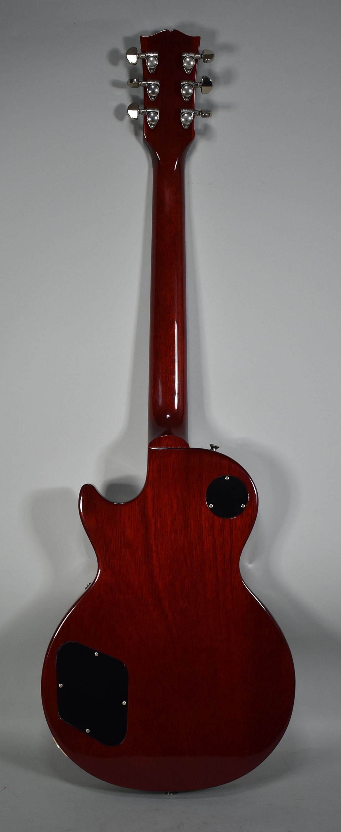 Full back view of a glossy dark cherry sunburst guitar with chrome tuners and two black control cavity covers.
