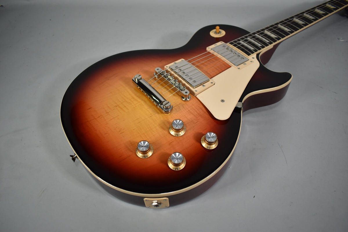 Sunburst electric guitar, angled from above, showing the body, cream pickguard, four gold-top knobs, and part of the neck.