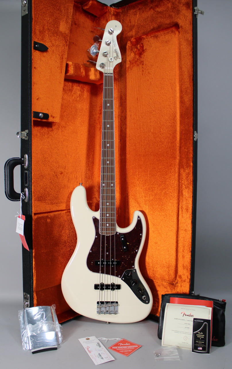 Full-length view of an Olympic White Jazz Bass with a tortoiseshell pickguard, chrome hardware, and a rosewood fretboard, in an open orange-lined case.