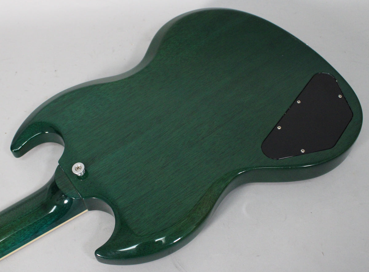 The back of a translucent teal SG guitar, showing the wood grain through the glossy finish, with a black control cavity cover.