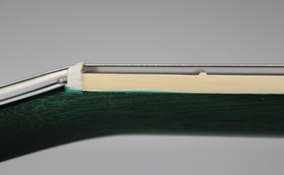 Close-up of the guitar's neck, showing the translucent teal finish, cream binding, and a white nut with strings.