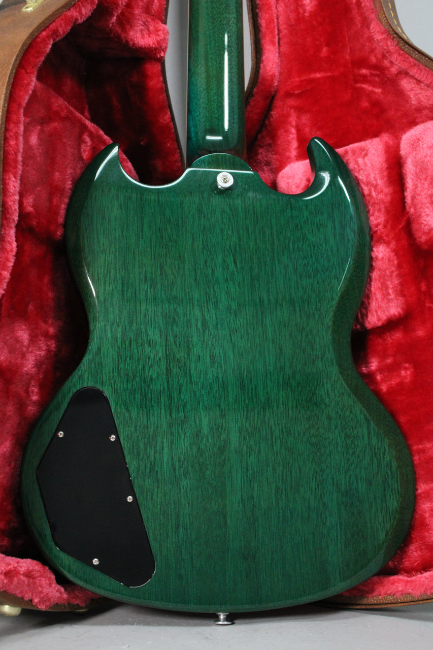 The back of a translucent teal SG guitar with visible wood grain, a black control cavity cover, and a strap button.