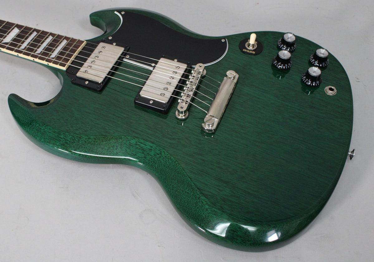 Close-up of a translucent teal SG electric guitar, showing the body, neck, black pickguard, two humbuckers, and four black control knobs.
