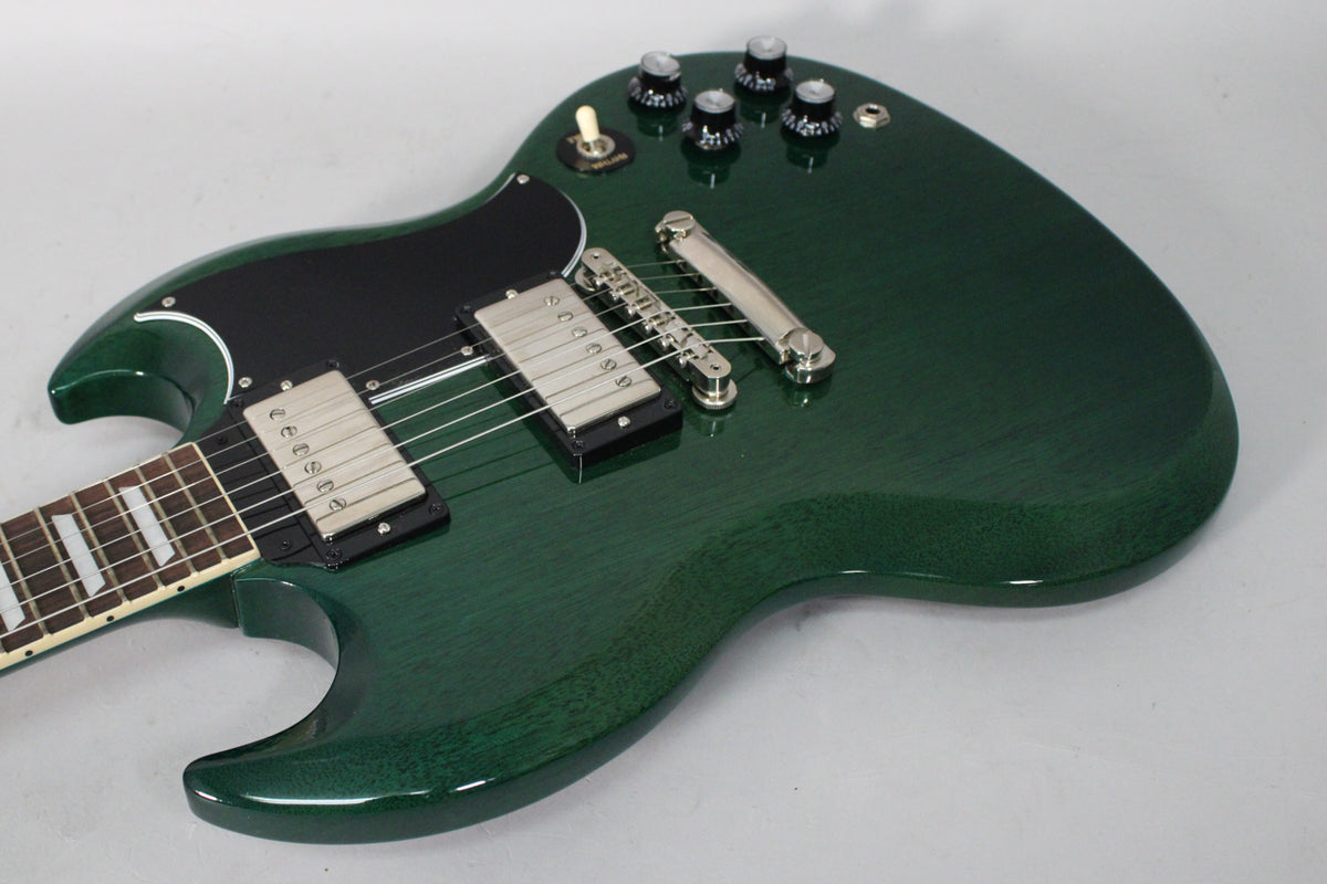The translucent teal SG body is angled from the neck, showing two humbuckers, a black pickguard, and four black control knobs.