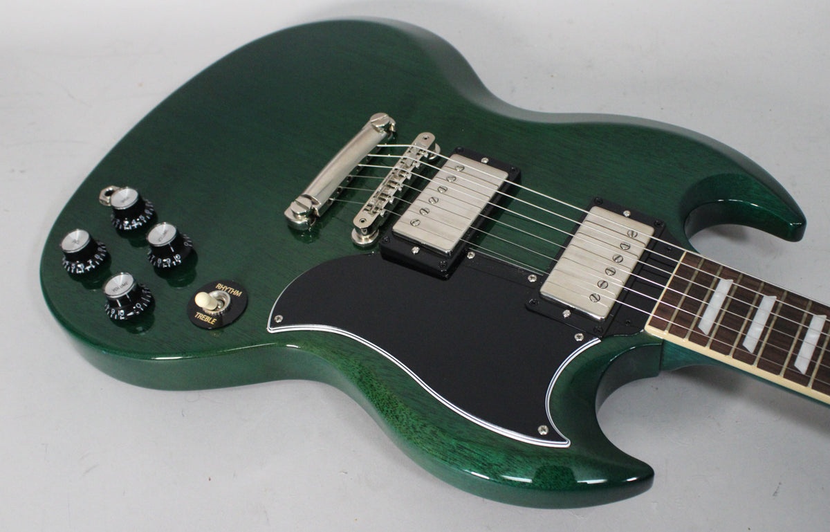 Translucent teal SG electric guitar, angled from above, showing the body, black pickguard, four black knobs, and two humbuckers.