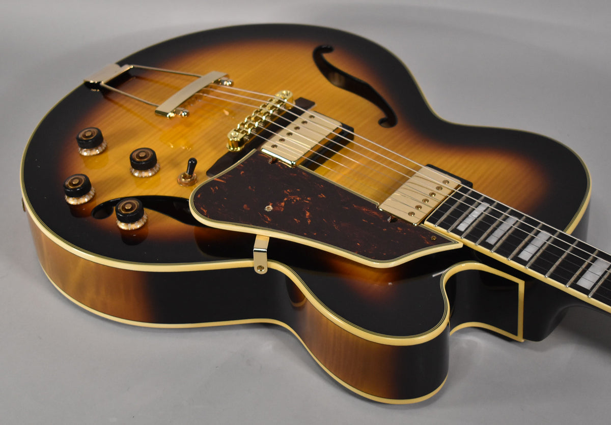 Sunburst archtop electric guitar, angled view of the body, showing gold hardware, f-holes, and a tortoiseshell pickguard.