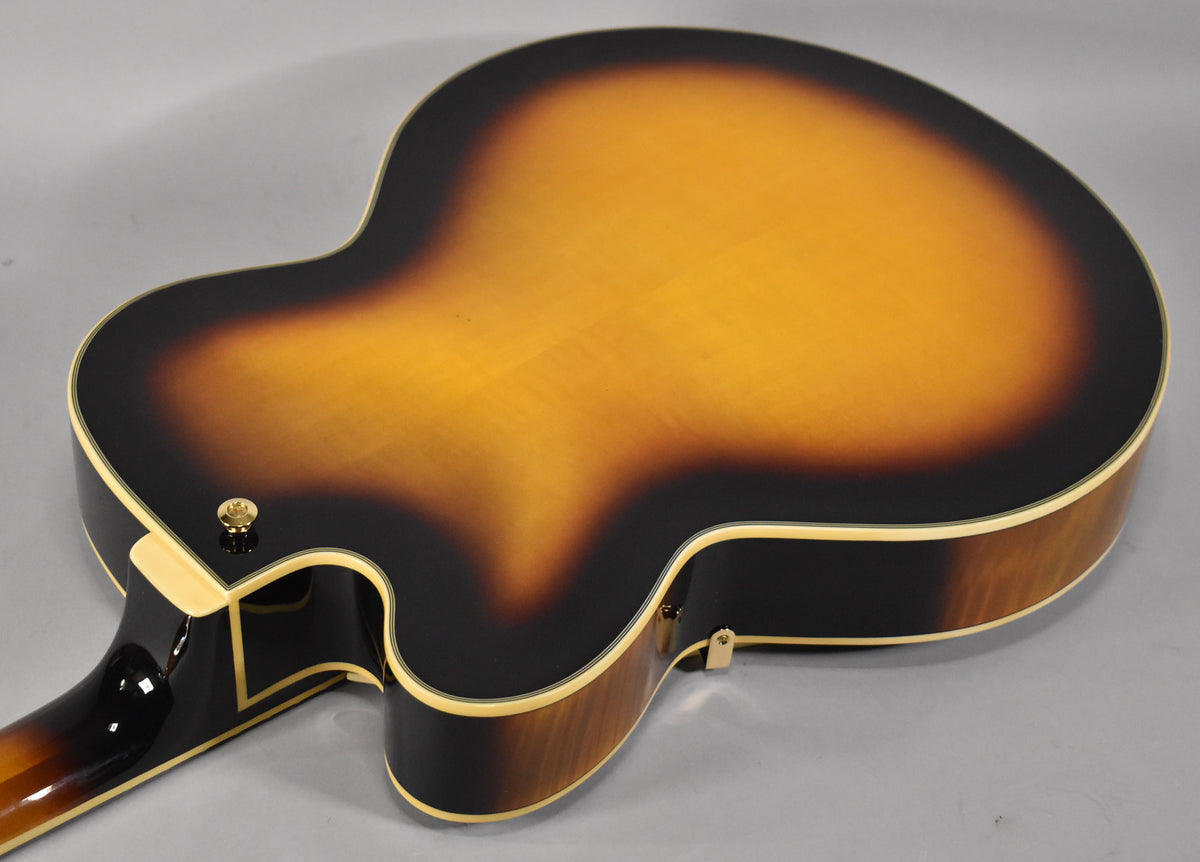 The guitar's sunburst back, with a gold strap button near the neck heel, shows a subtle flame maple grain.