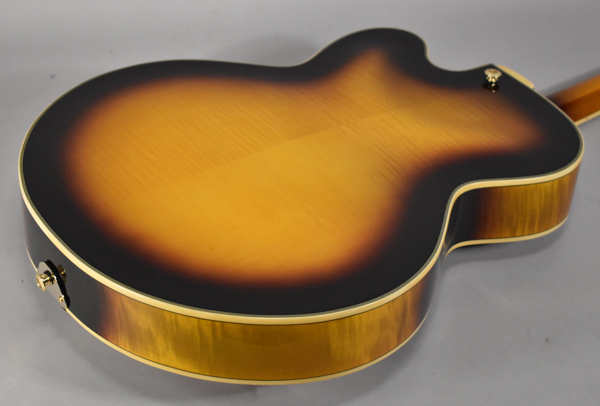 The guitar's sunburst back and sides are visible, with a subtle flame maple grain and cream binding around the body.