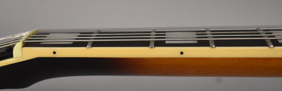 Close-up of the guitar's neck, showing the dark fretboard with rectangular inlays, cream binding, and sunburst finish on the neck.