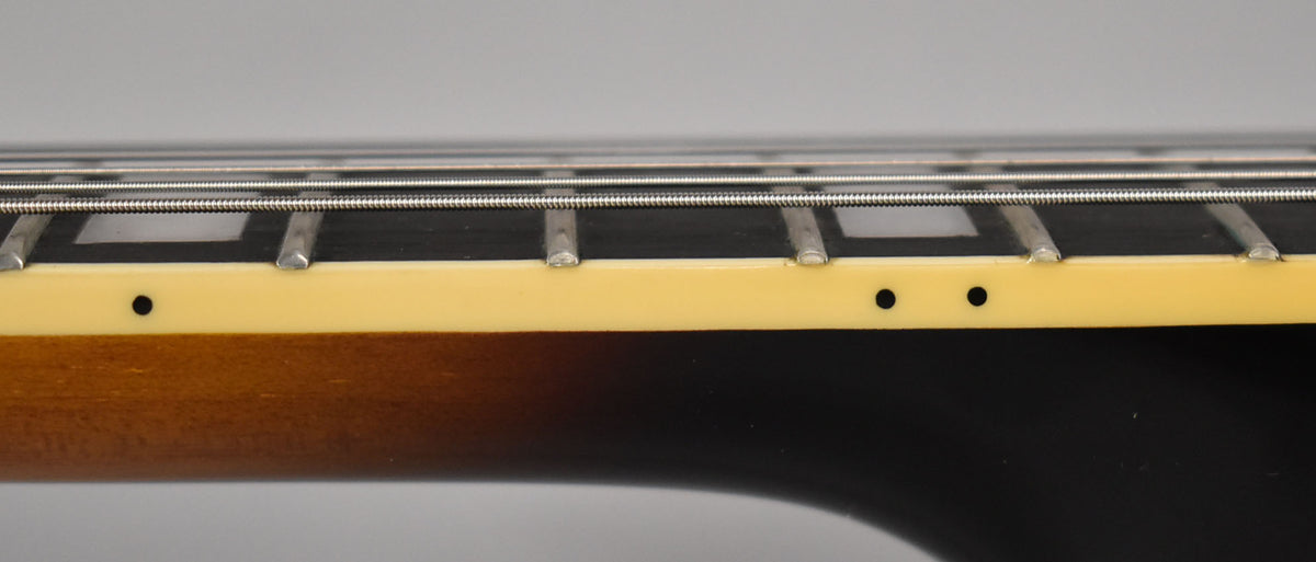 Close-up of the guitar's fretboard, showing block inlays, side dots, and a cream binding along the sunburst neck.