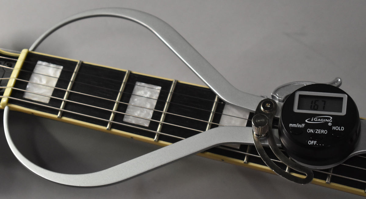 A digital string action gauge measures the distance between the strings and the fretboard, displaying "1.67" mm.