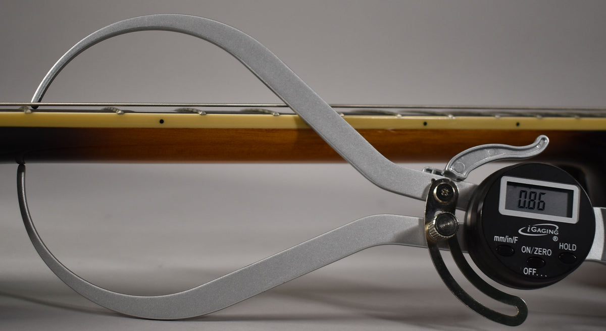A digital caliper measures the string height at the 12th fret of the sunburst archtop, showing 0.86mm.