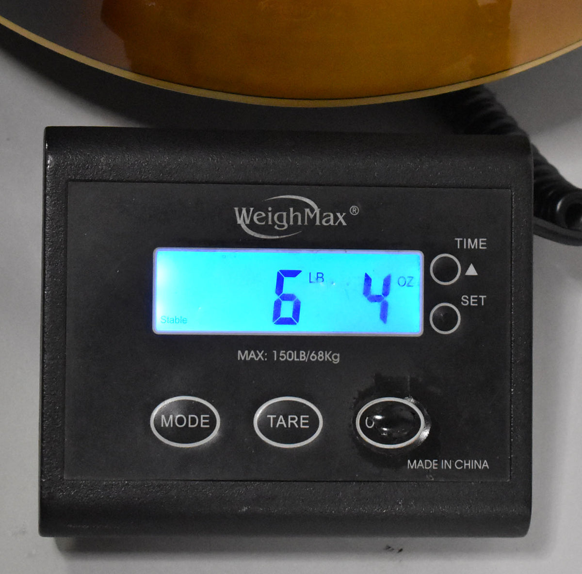 A close-up of a digital scale displaying "6 LB. 4 OZ." with the guitar's sunburst body visible at the top.