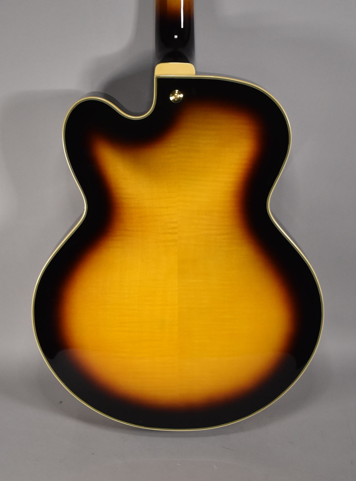 The guitar's glossy sunburst back shows a flame maple grain, with a gold strap button near the neck heel.