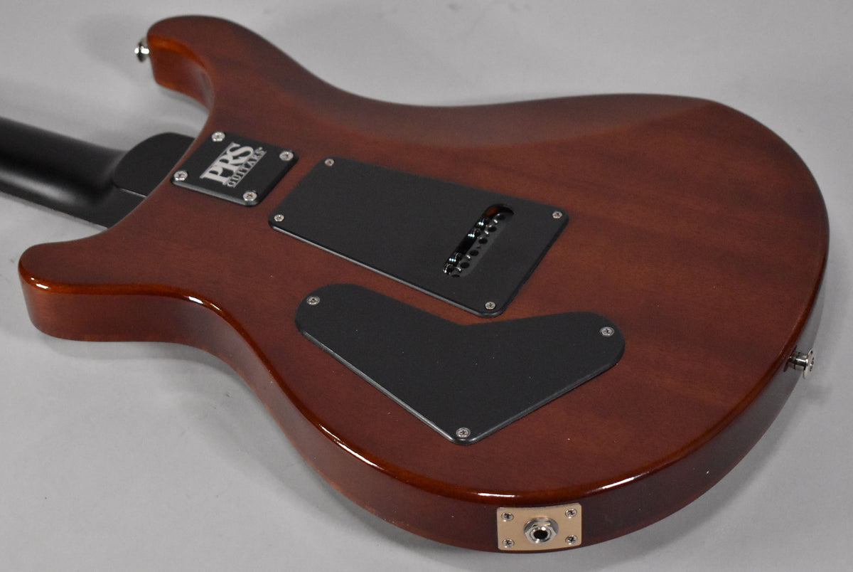 The back of a reddish-brown electric guitar, showing the neck joint, two black control plates, and a chrome output jack.