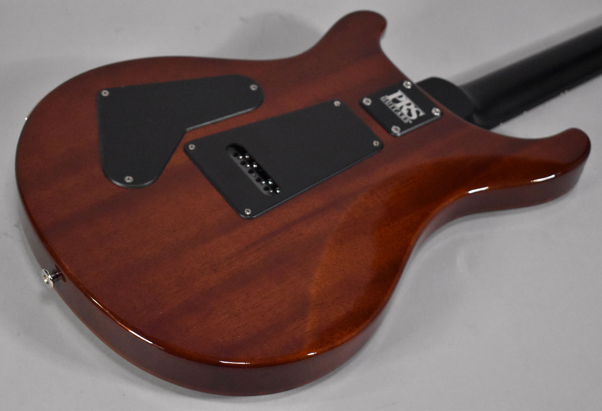 The back of a glossy reddish-brown electric guitar, showing two black control cavity covers and a black neck heel.