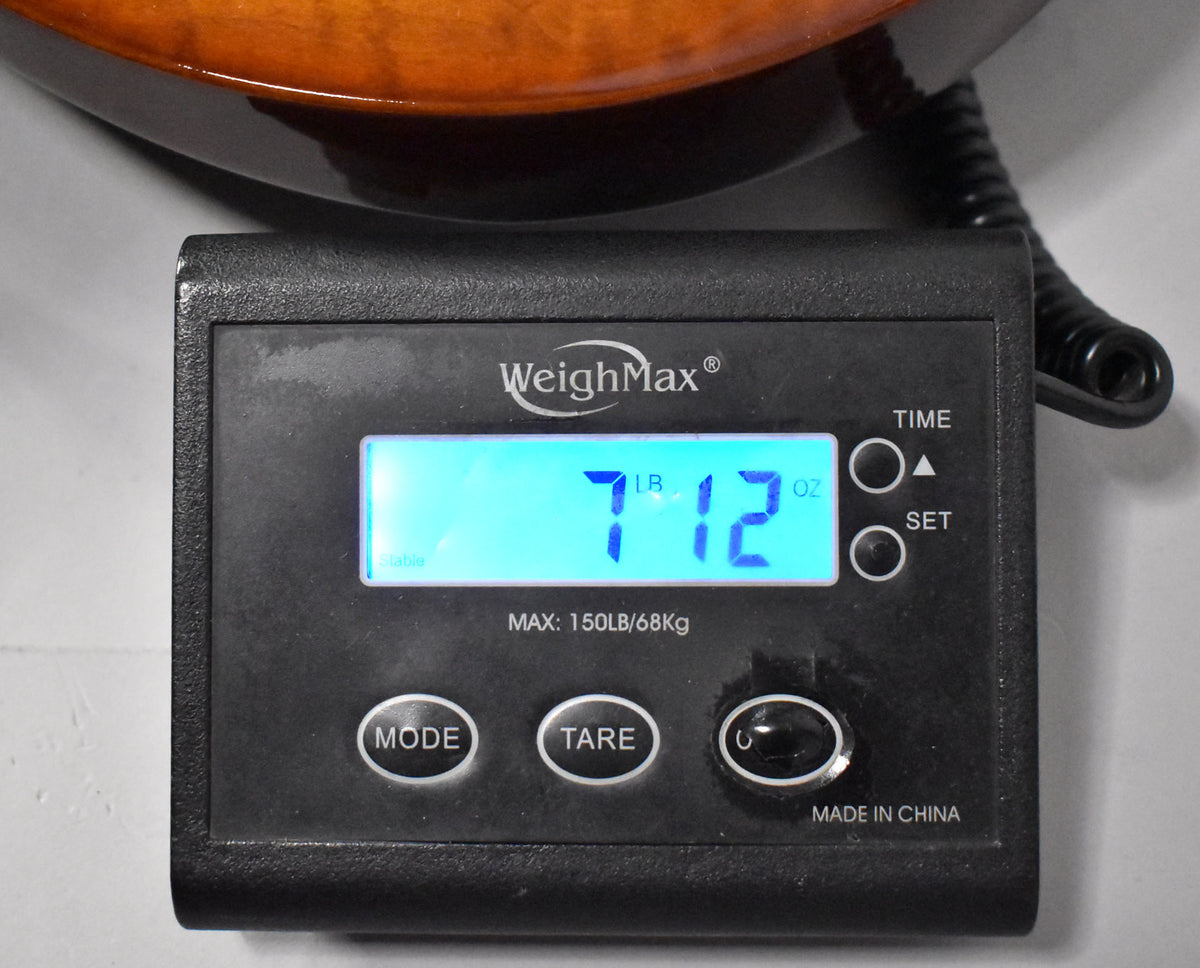 A digital scale displays the guitar's weight as 7 pounds, 12 ounces, with the guitar's amber body visible at the top.