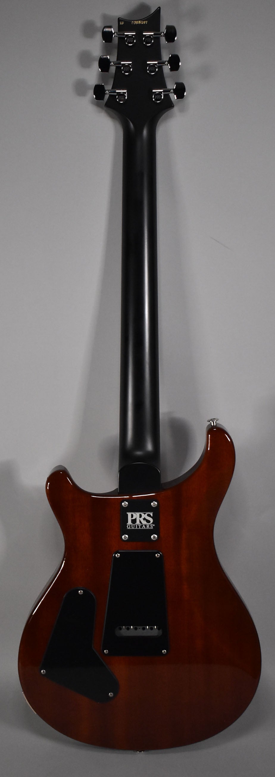 The guitar's back, a glossy dark reddish-brown, shows a black neck, headstock with six chrome tuners, and black control cavity covers.