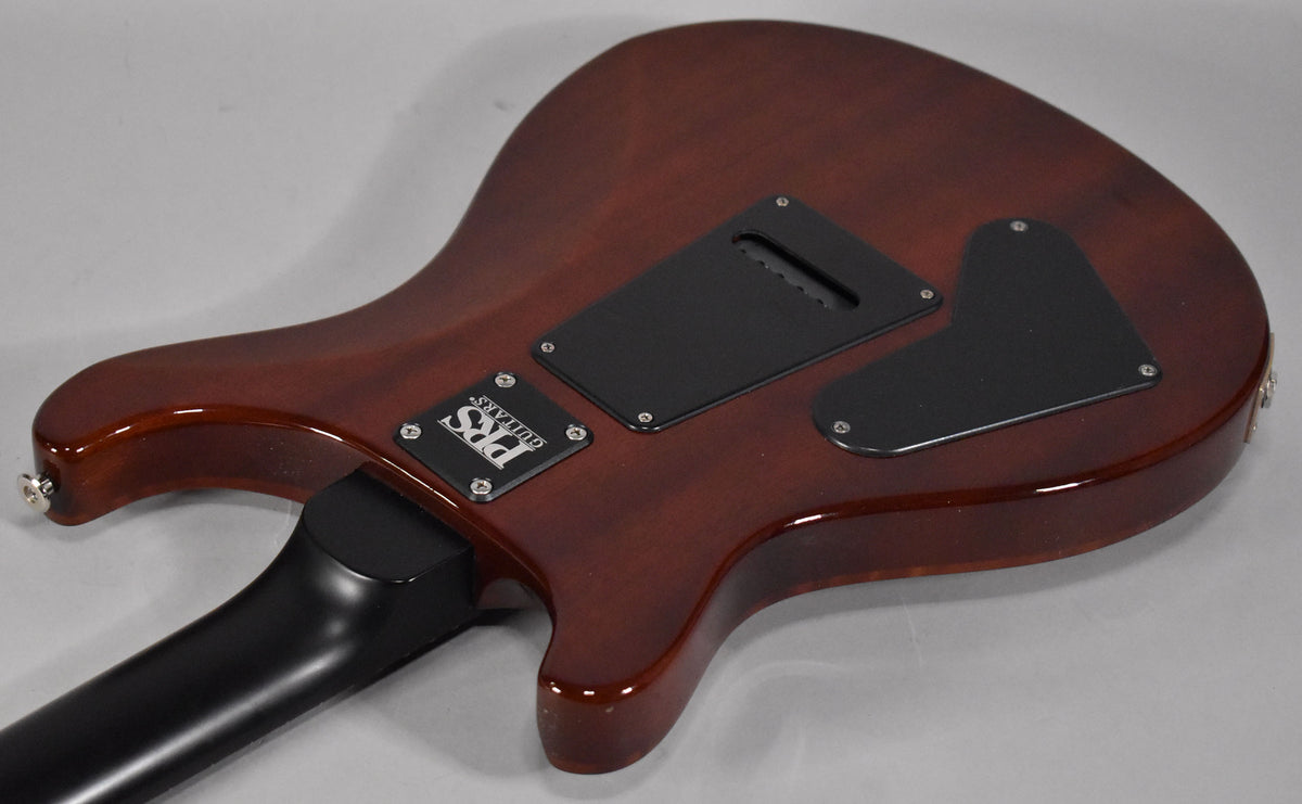 The guitar's mahogany back, angled from the lower bout, shows two black control cavity covers and a black neck heel.