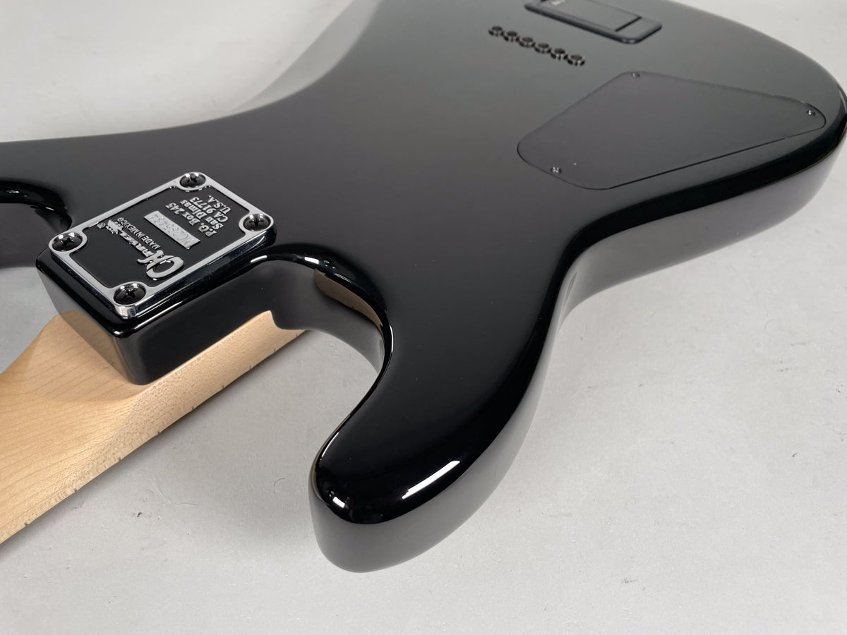 The guitar's glossy black body, with a neck plate and control cavity cover, curves towards a light wood neck.