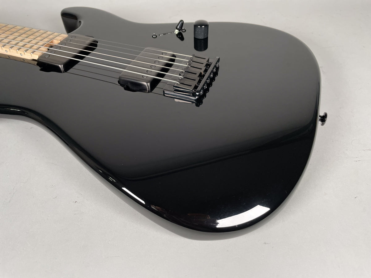 Close-up of the glossy black guitar body, showing the bridge, two humbucker pickups, and a single black control knob.